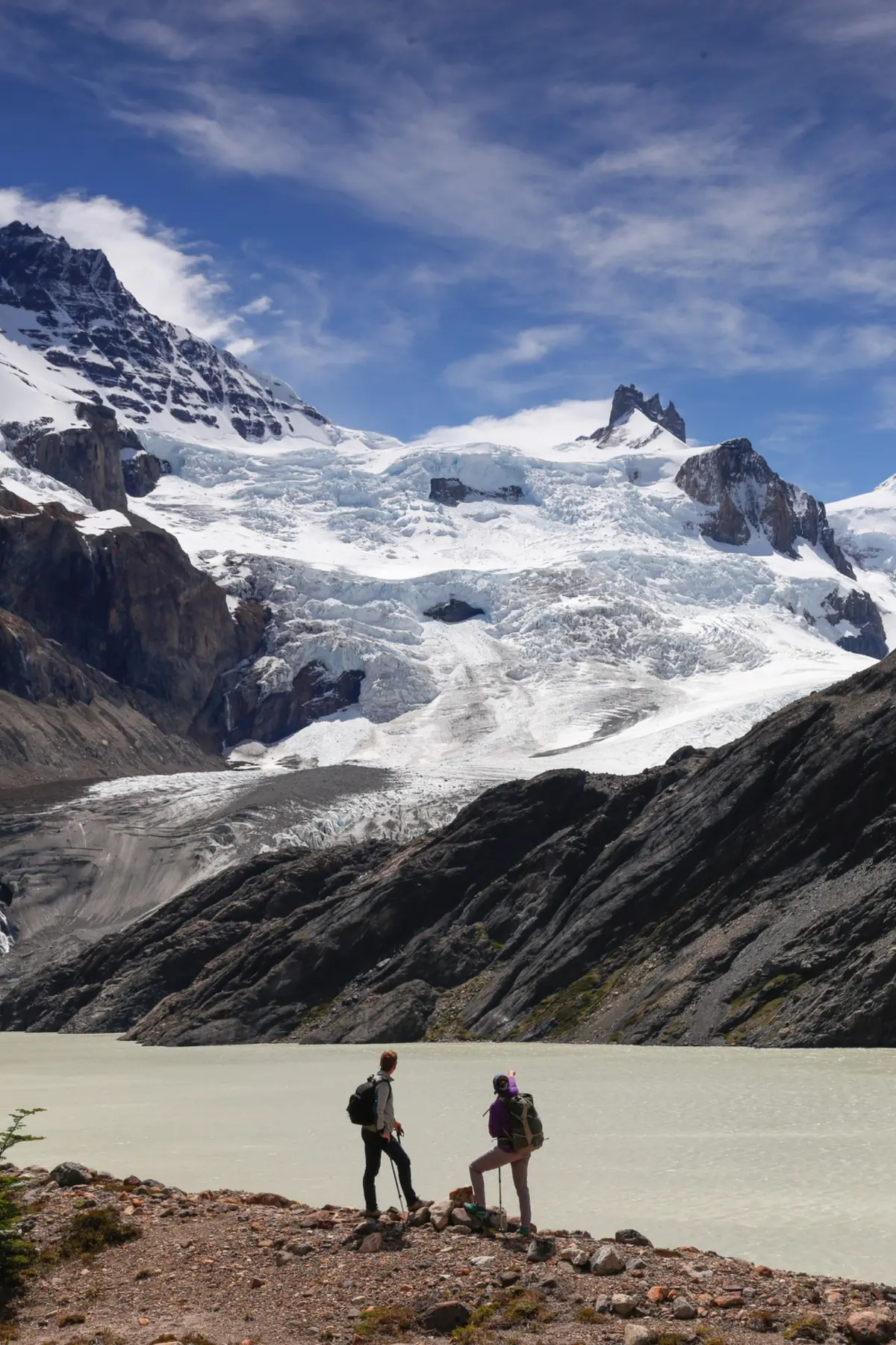 Two walkers observing a glacier and mountain lake in Patagonia